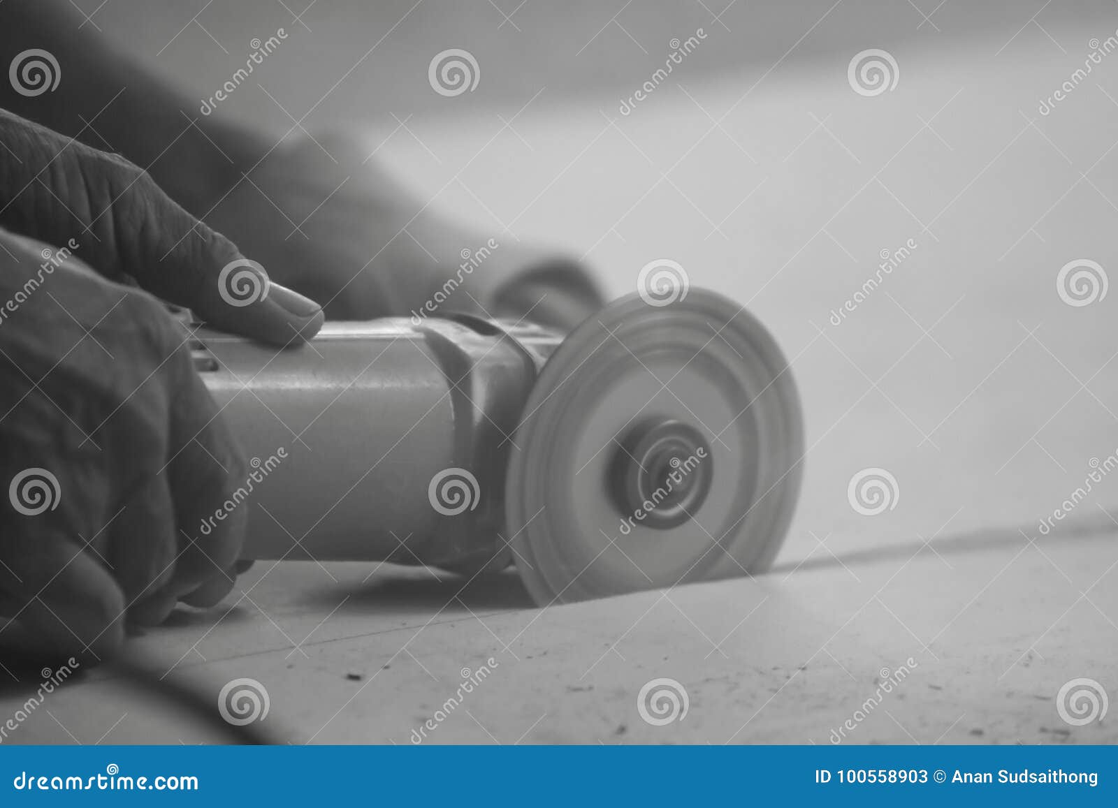 monochrome toned image of angle grinder cutting concrete with hands of heavy industry worker.