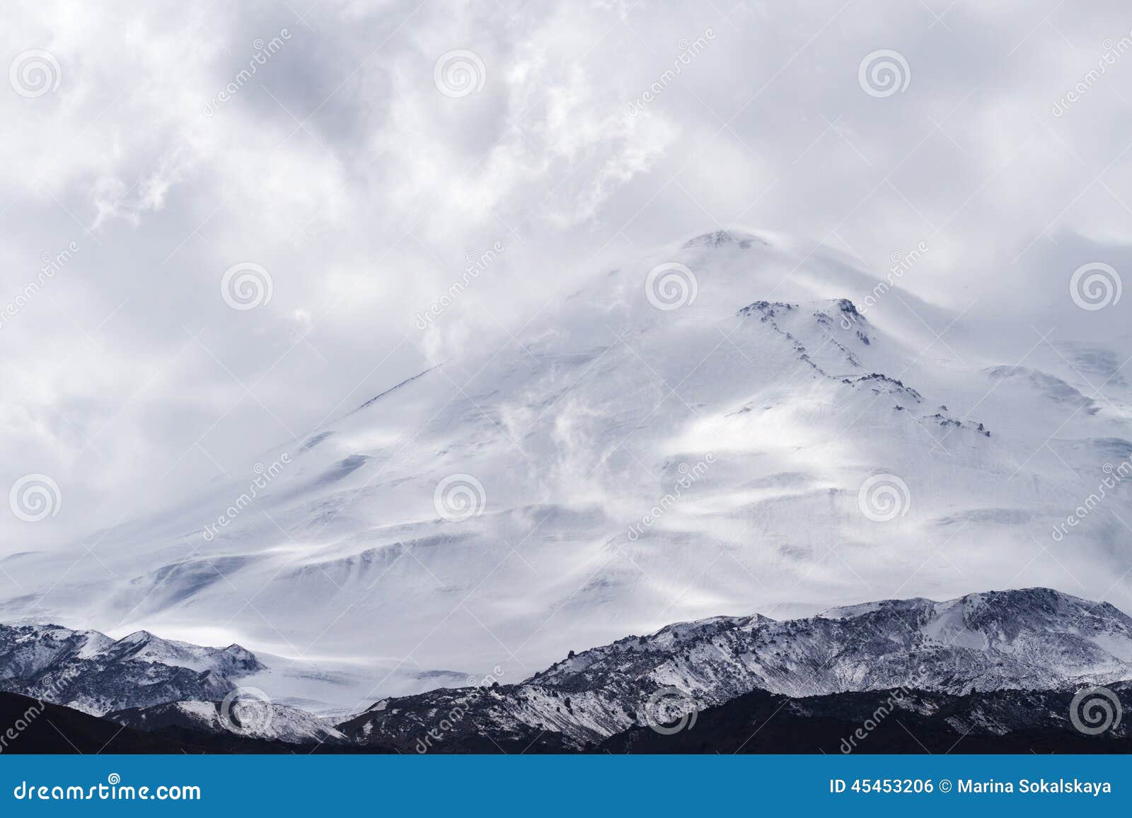 Montaña capsulada nieve de Elbrus. La montaña coronada de nieve de Elbrus rodeada por las nubes sube sobre el área de montaña en Kabardino-Balkaria (el Cáucaso, Rusia) La foto se ha tirado en septiembre de 2014 Puede ser utilizado como un fondo, un papel pintado o postal
