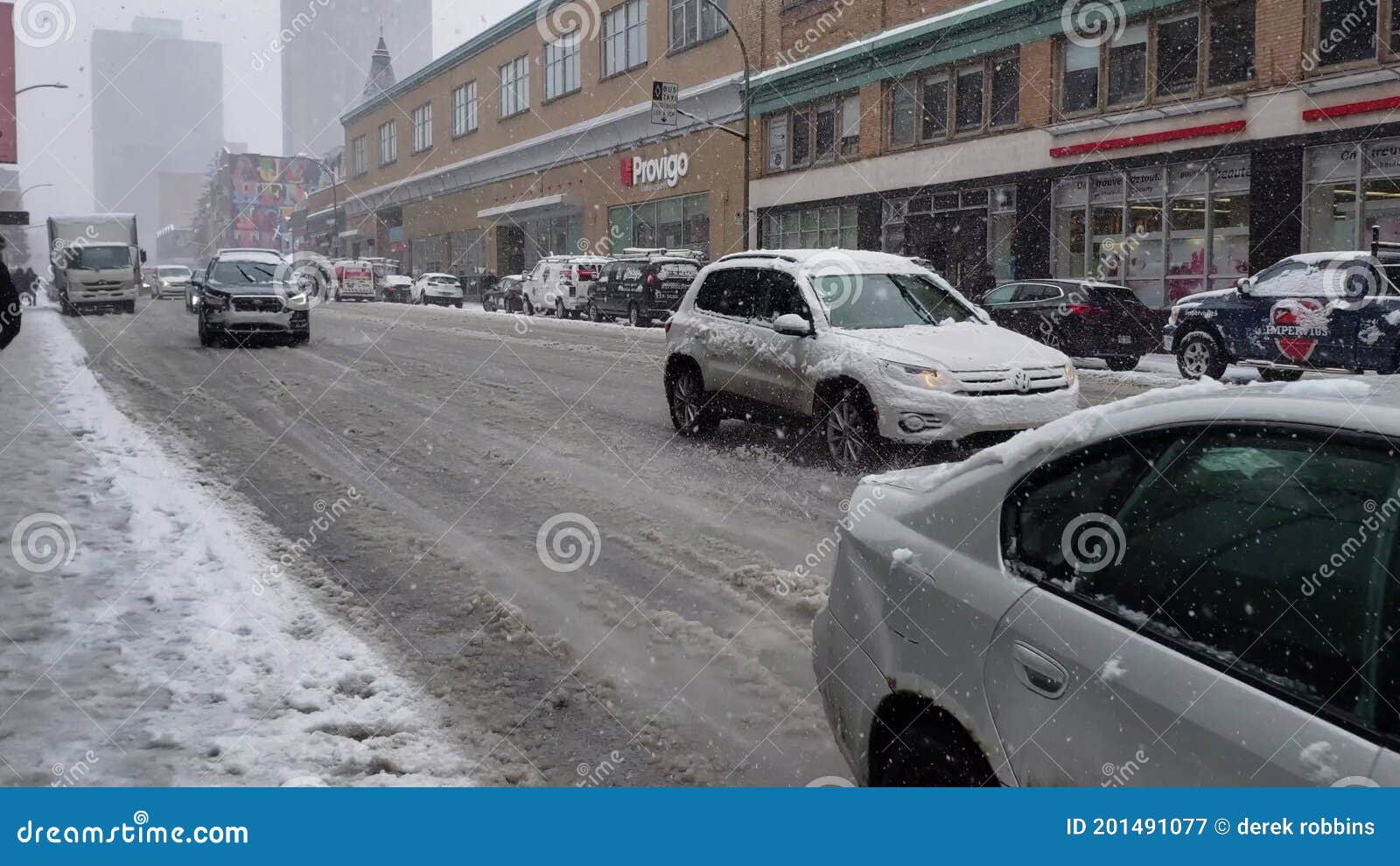 Cars driving down slushy road well snowing