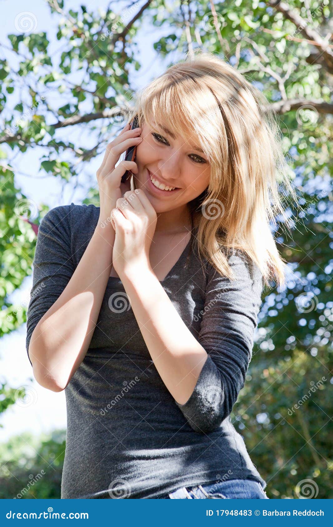 Mooi Meisje dat op Mobiele Telefoon, de Telefoon van de Cel spreekt. Vrij blonde tiener die op celtelefoon spreekt (mobiele telefoon) in openlucht op een zonnige dag.