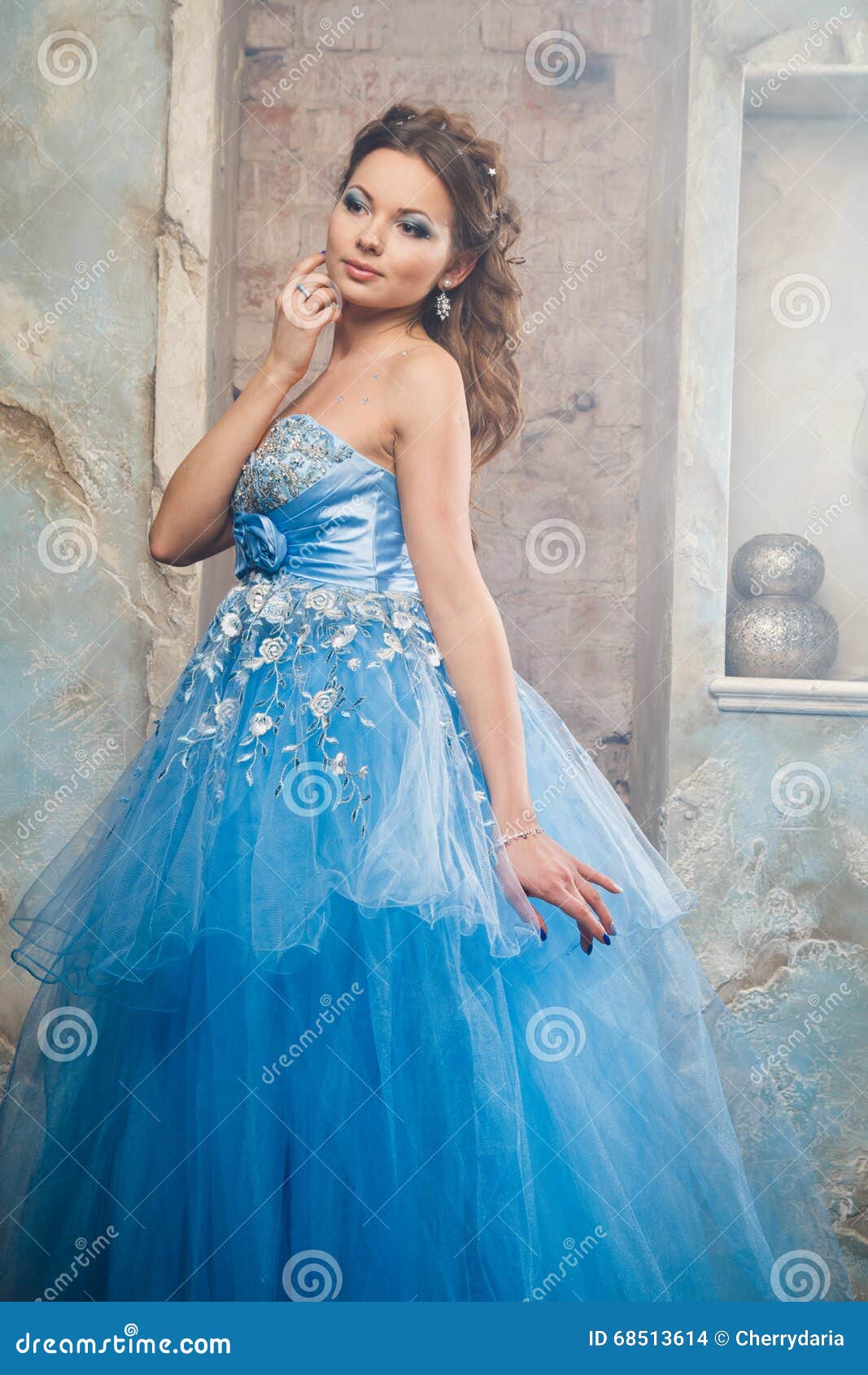 Mooie jonge vrouw in schitterende blauwe lange kleding zoals Cinderella met perfecte samenstelling en haarstijl in binnenland