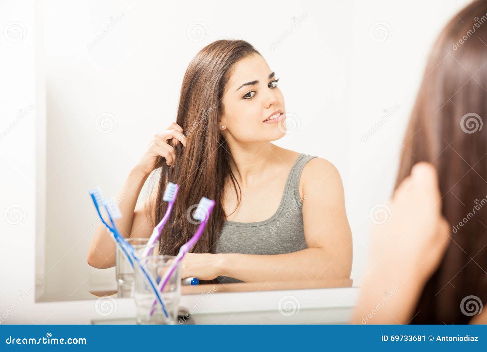 Morena bonita que escova seu cabelo. Retrato de uma morena latino-americano nova lindo que escova e que denomina seu cabelo no banheiro