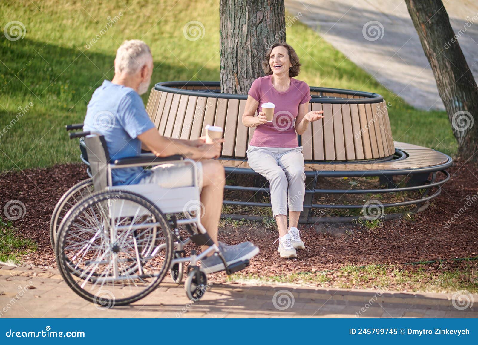 a man in a wheel chair and a woman havinng coffee in the park