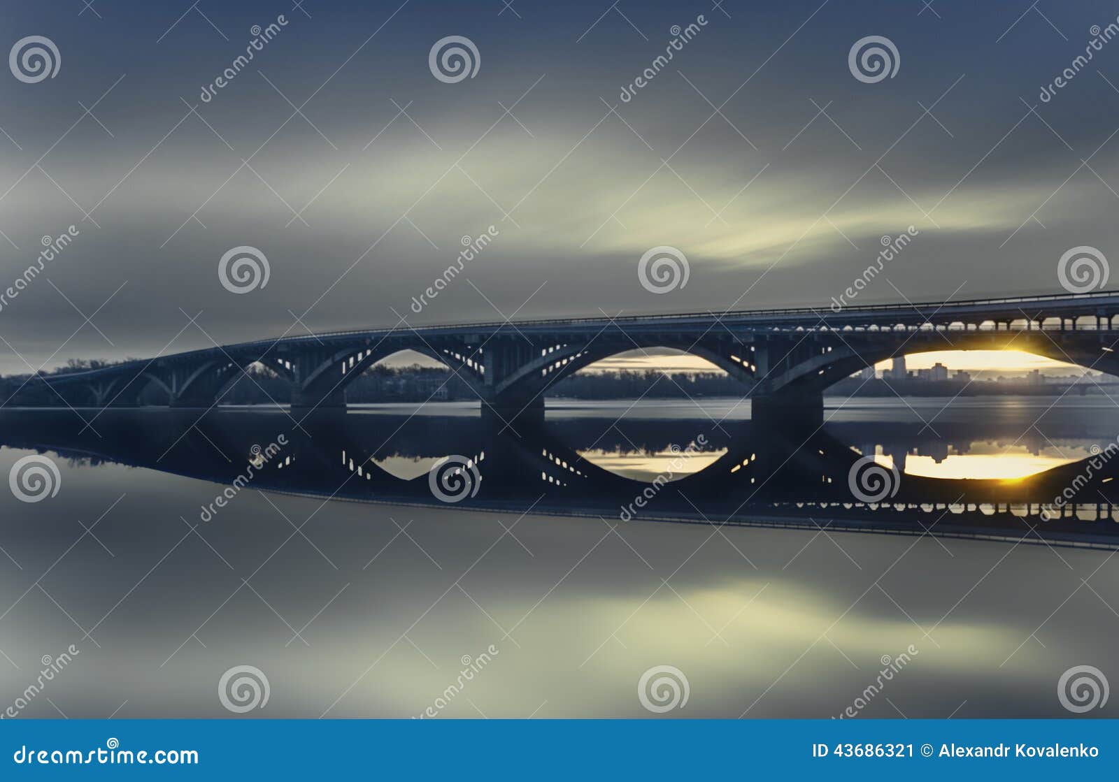 Morning silence. Photo of the bridge over the river, the surface water transfers greatness facilities. The sun reflected on the water surface slips under the bridge.