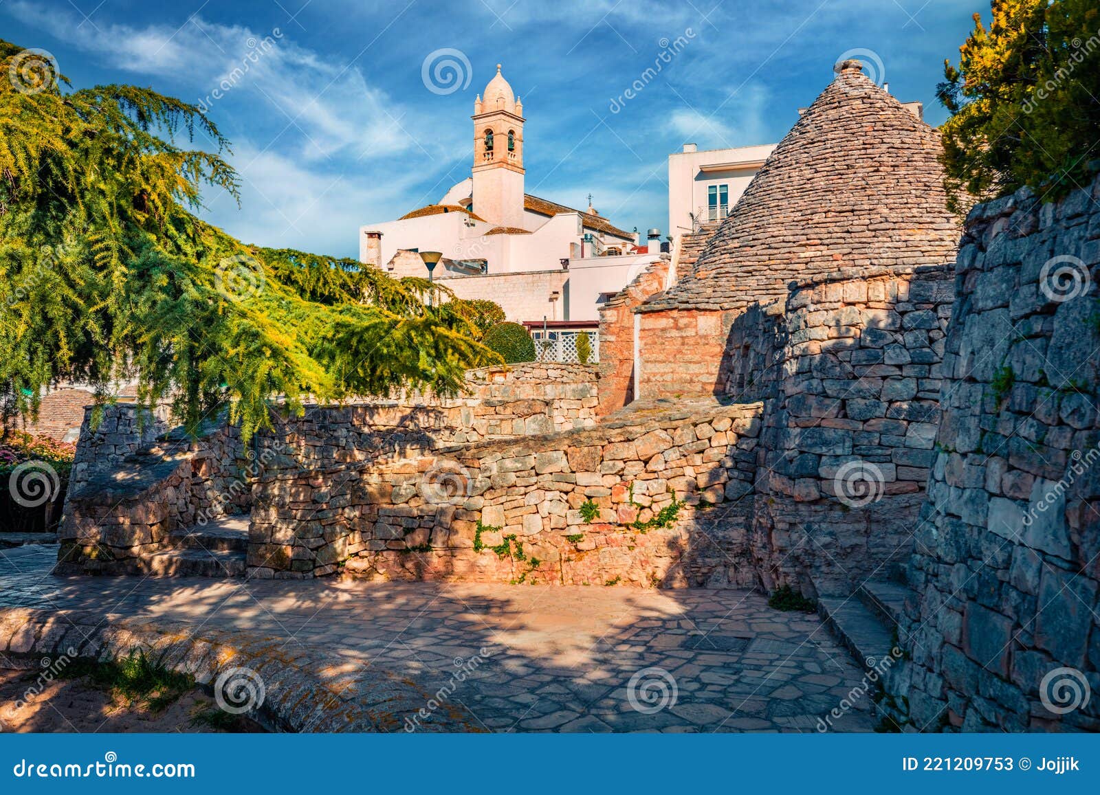 morning view of strret with trullo trulli - traditional apulian dry stone hut with a conical roof. spring cityscape of alberobe