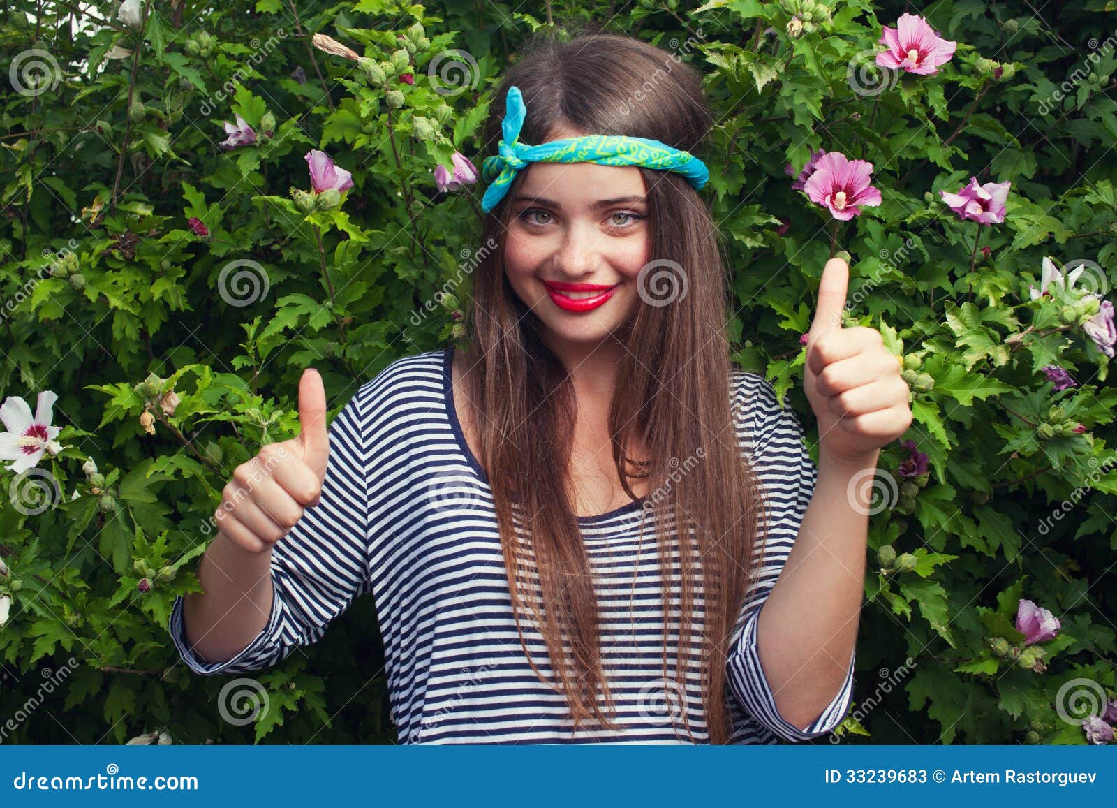 Modello d'avanguardia dell'adolescente con la bandana che posa con i fiori. All'aperto. Mostrando doppio pollice su