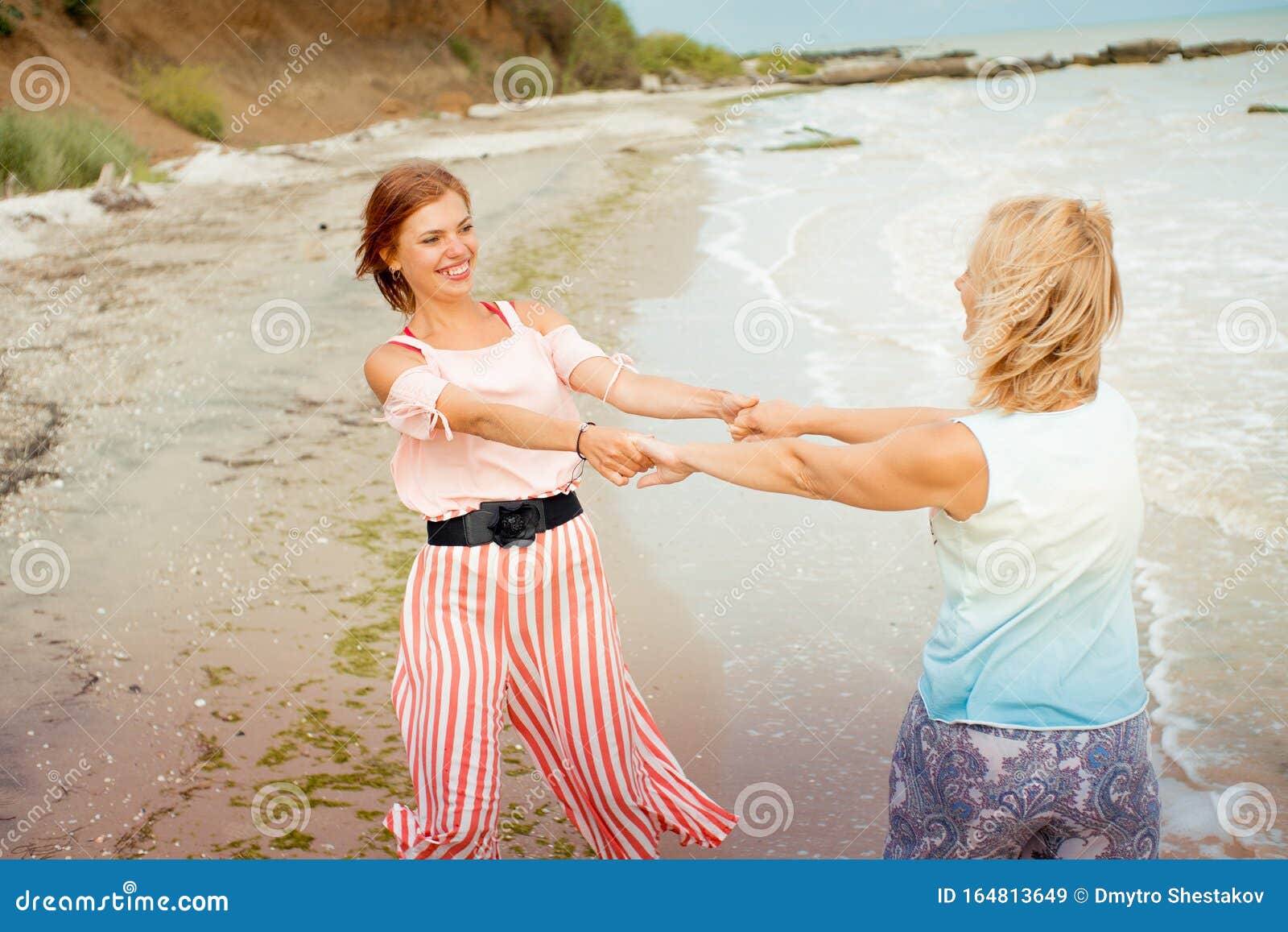 Mother And Adult Daughter Spinning On The Sea Shore Holding Hands Stock Image Image Of 