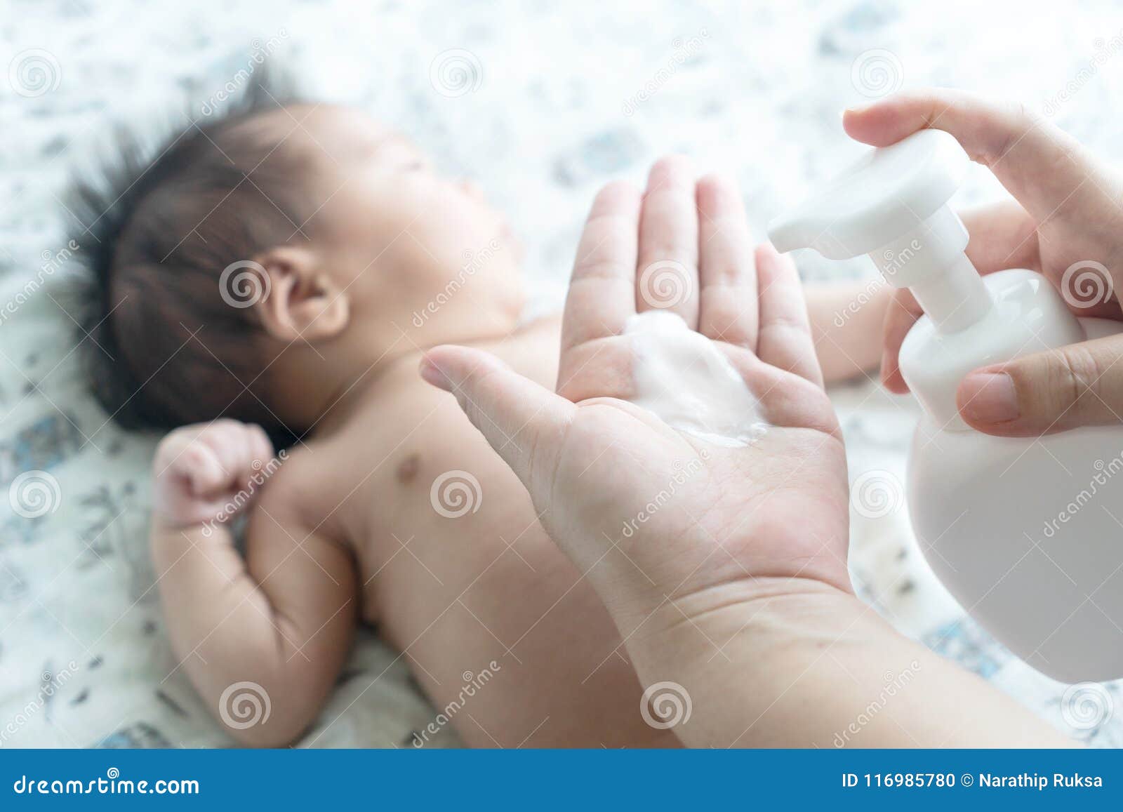 mother are applying a lotion cream on the baby body after bath