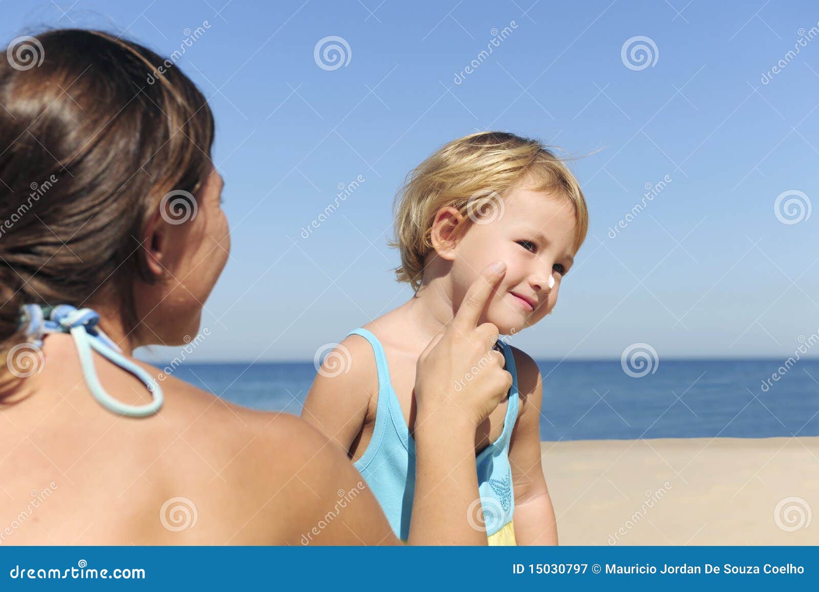 mother applying suntan lotion to her daughter