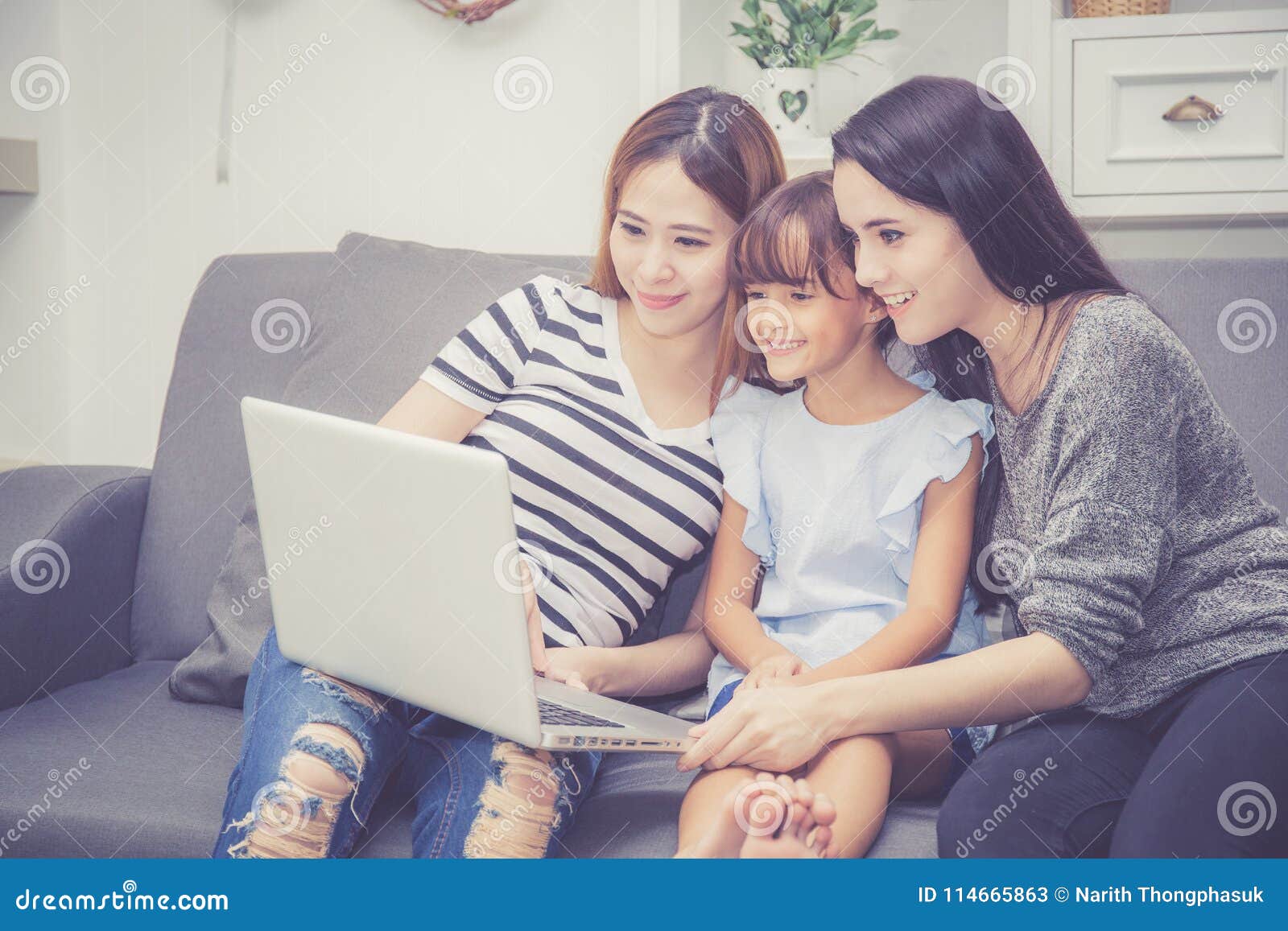 mother, aunt and kid having time together lerning with using laptop computer at home with relax and happy on couch