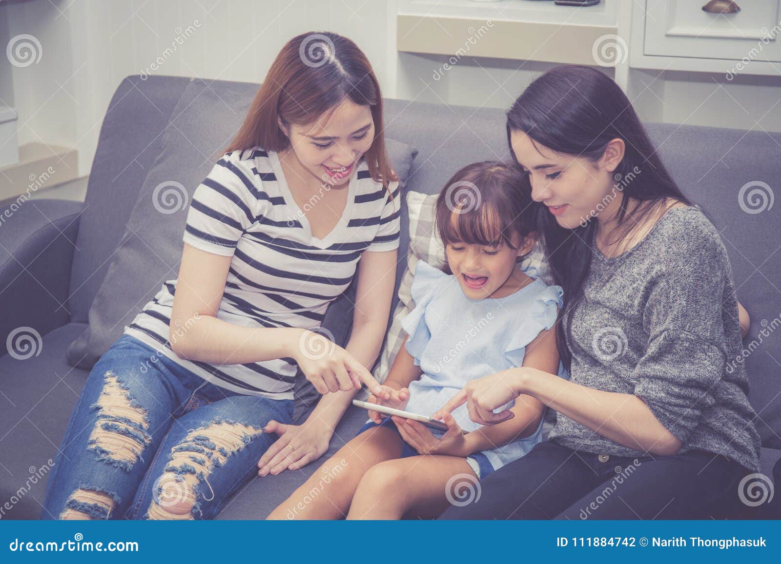mother, aunt and kid having time together lerning with using tablet at home with relax and happy on couch