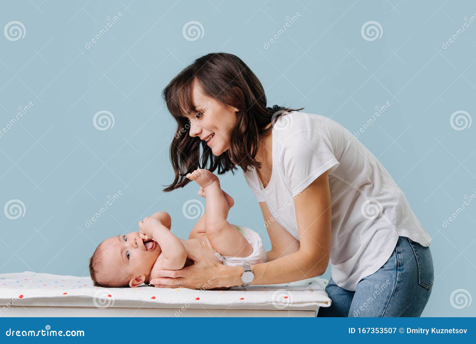 mother bent over her infant talking, caring and playing with him