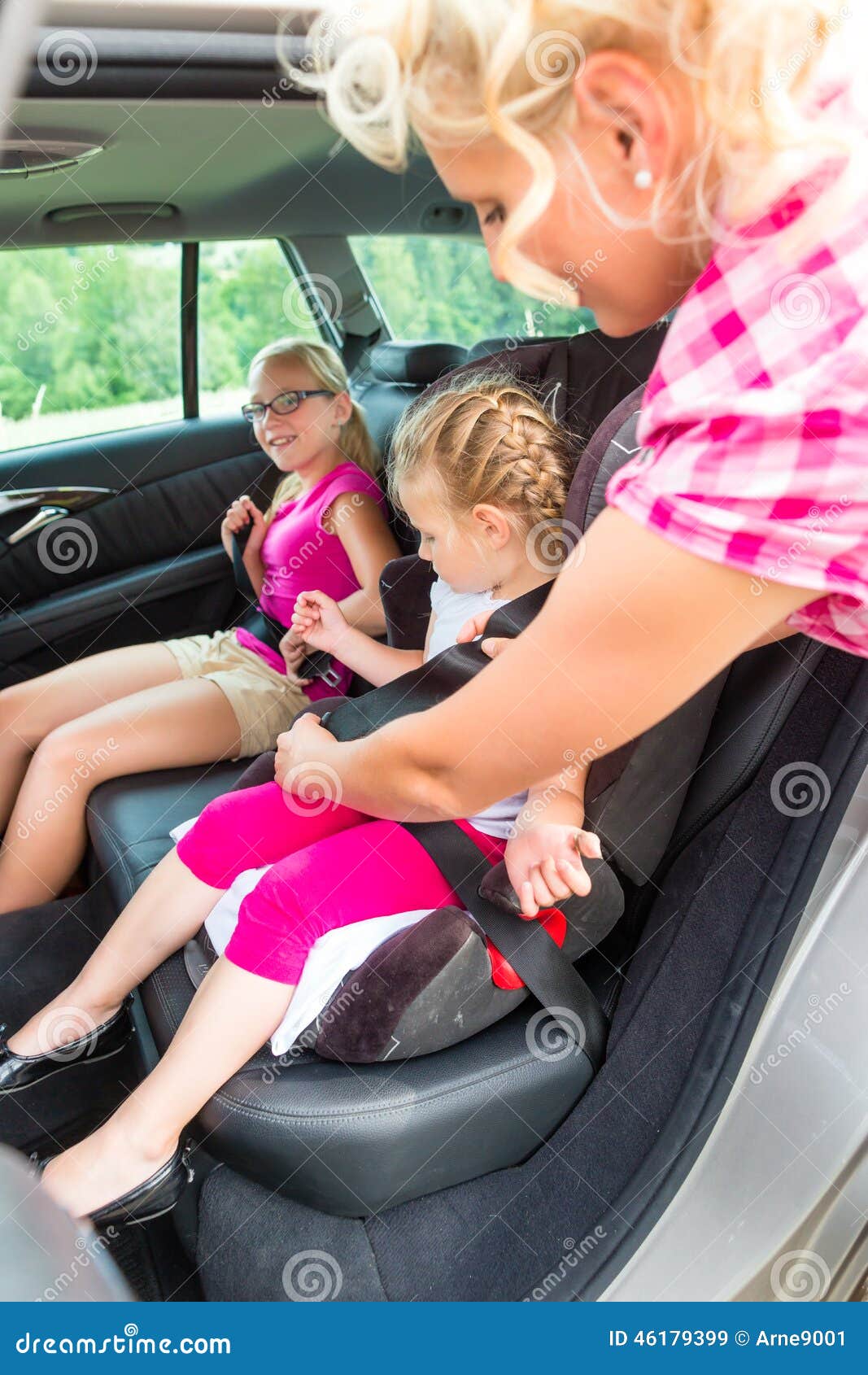 mother buckling up on child in car