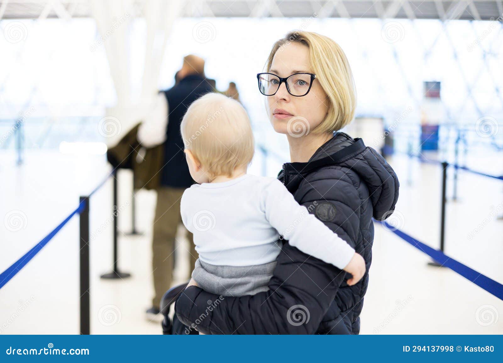 mother carying his infant baby boy child queuing at airport terminal in passport control line at immigrations departure