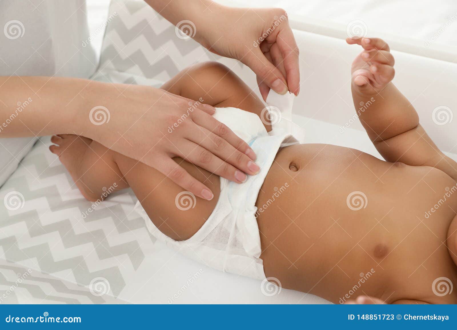 mother changing her baby`s diaper on table