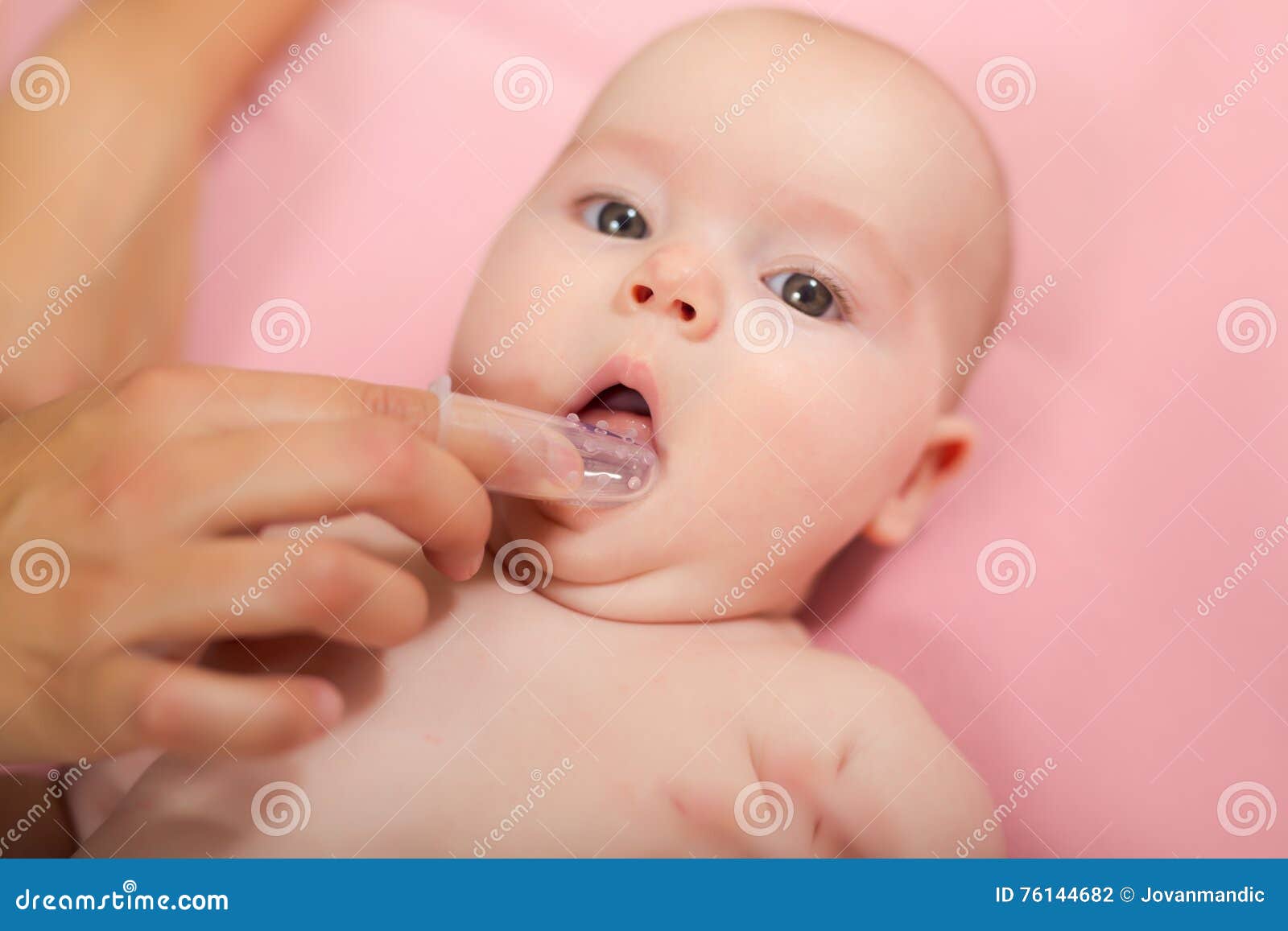 mother cleaning baby`s mouth with special fingertip brush