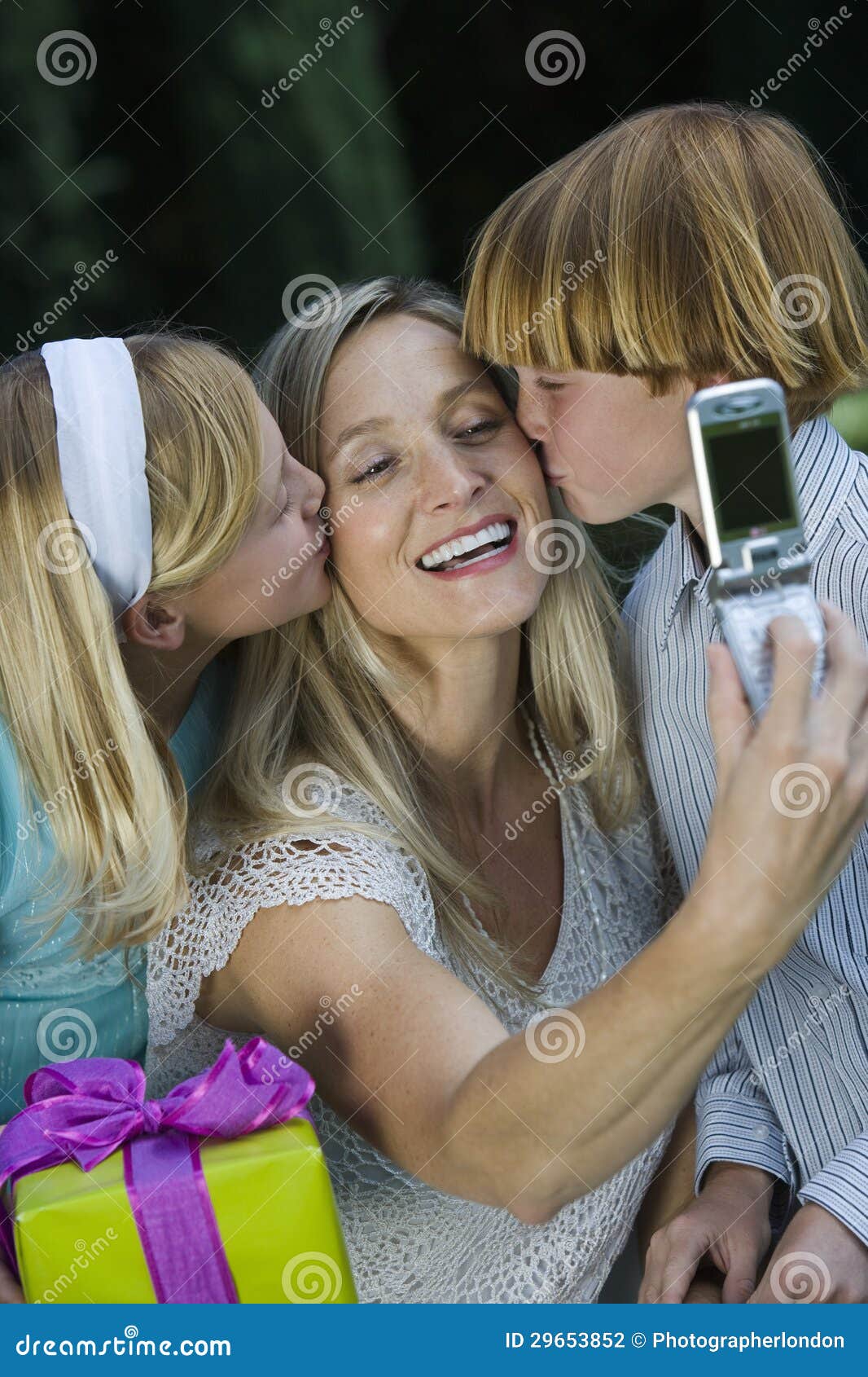 mother clicking self photo while kids kissing