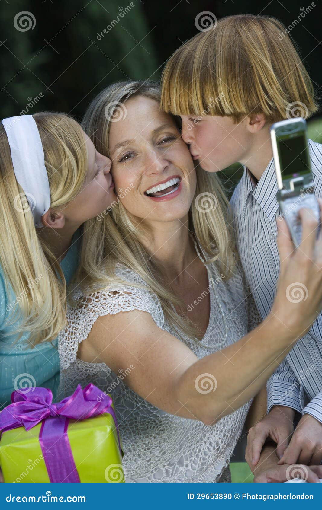 mother clicking self photo while kids kissing