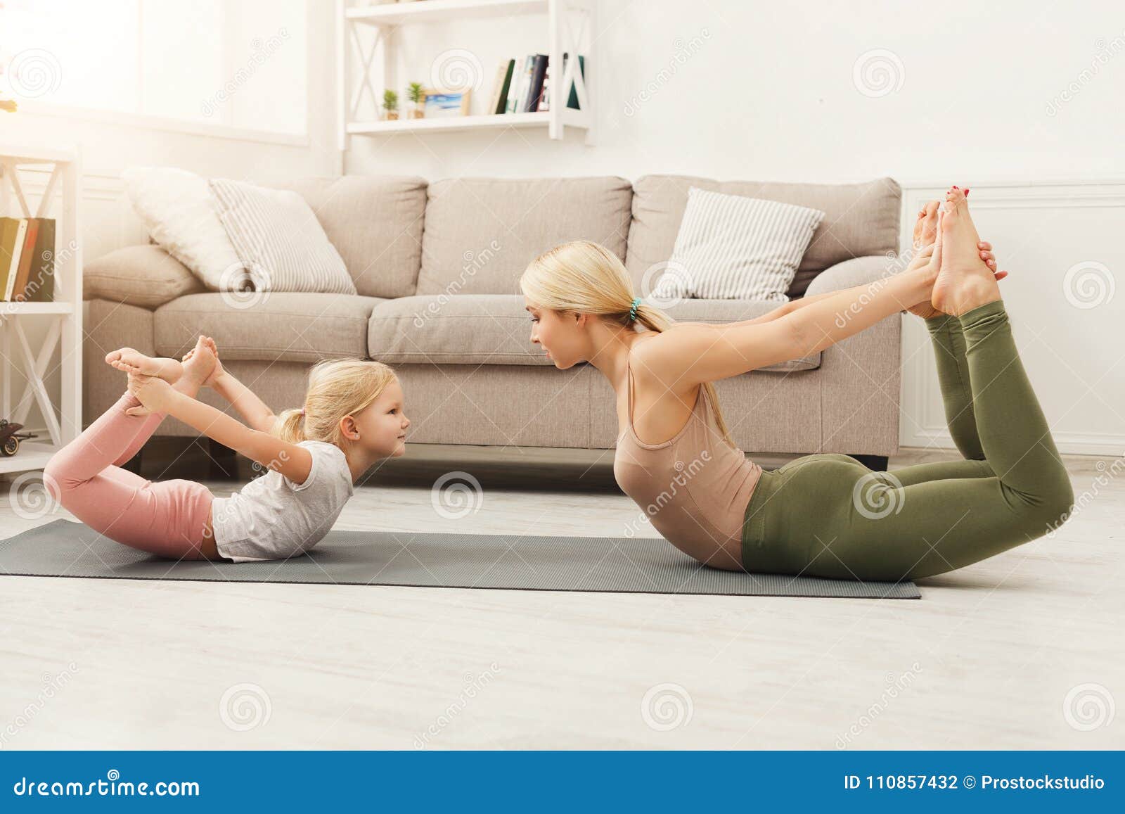 Mother And Daughter Doing Yoga Exercises At Home Stock