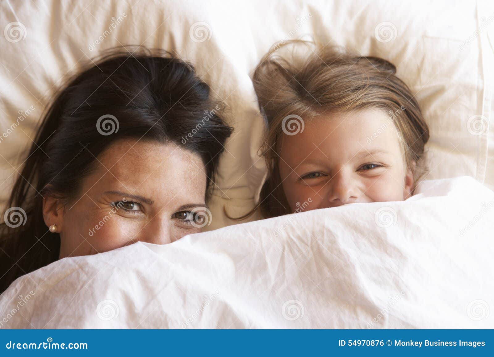 mother and daughter hiding under bedclothes