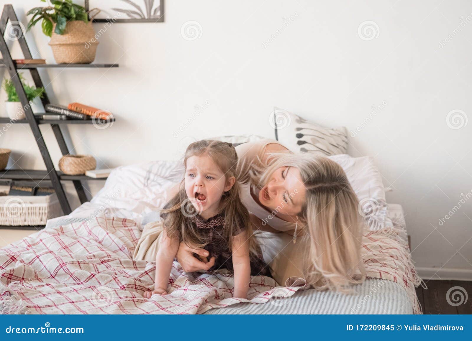 Mother And Daughter Jumping On Bed Having Fun Together Stock Image