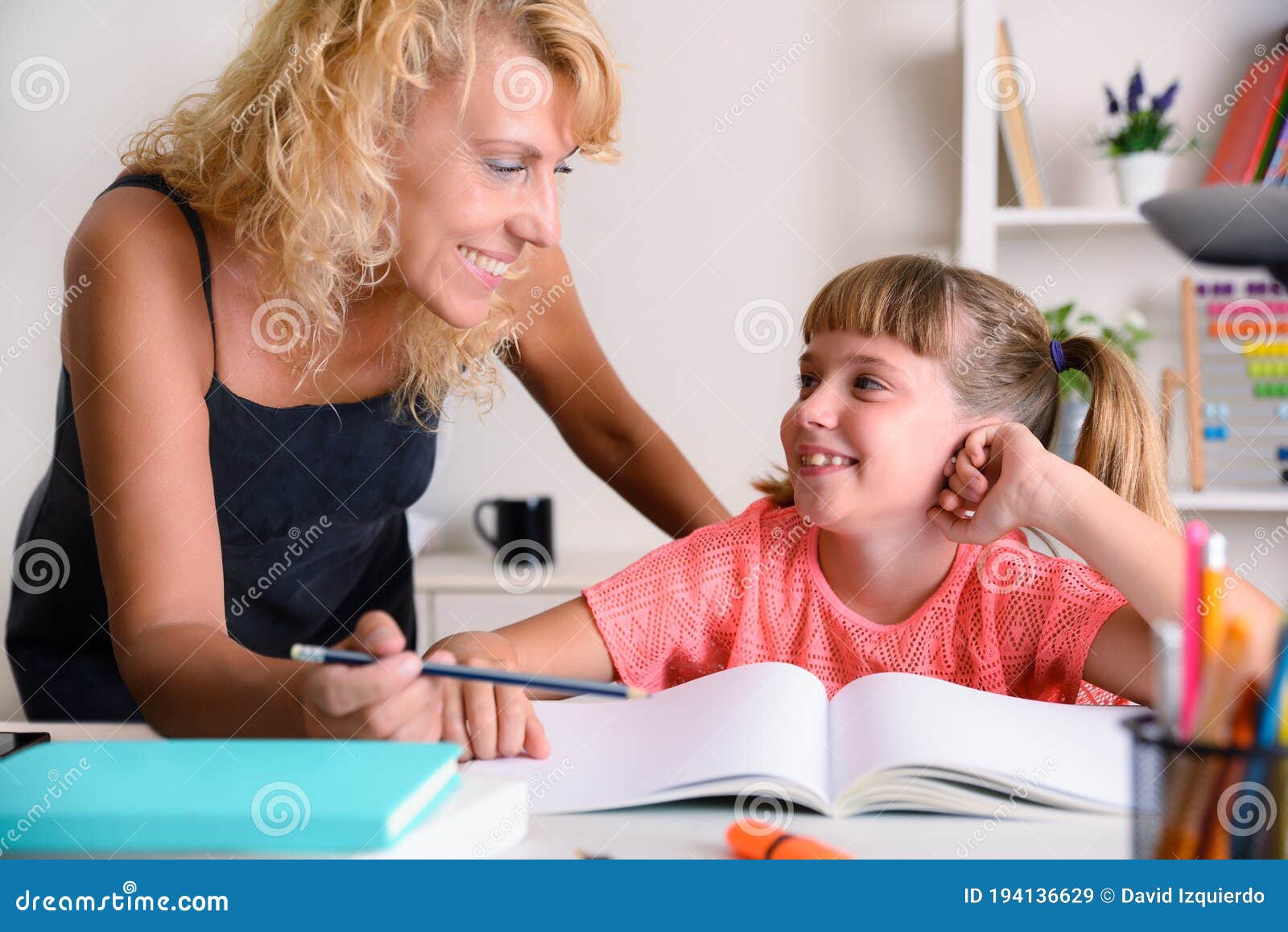 mother and daughter looking with complicity in school studies home