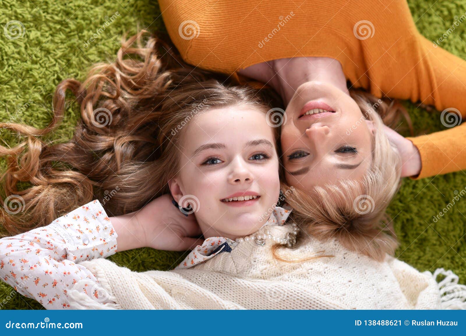 mother with daughter lying on green carpet