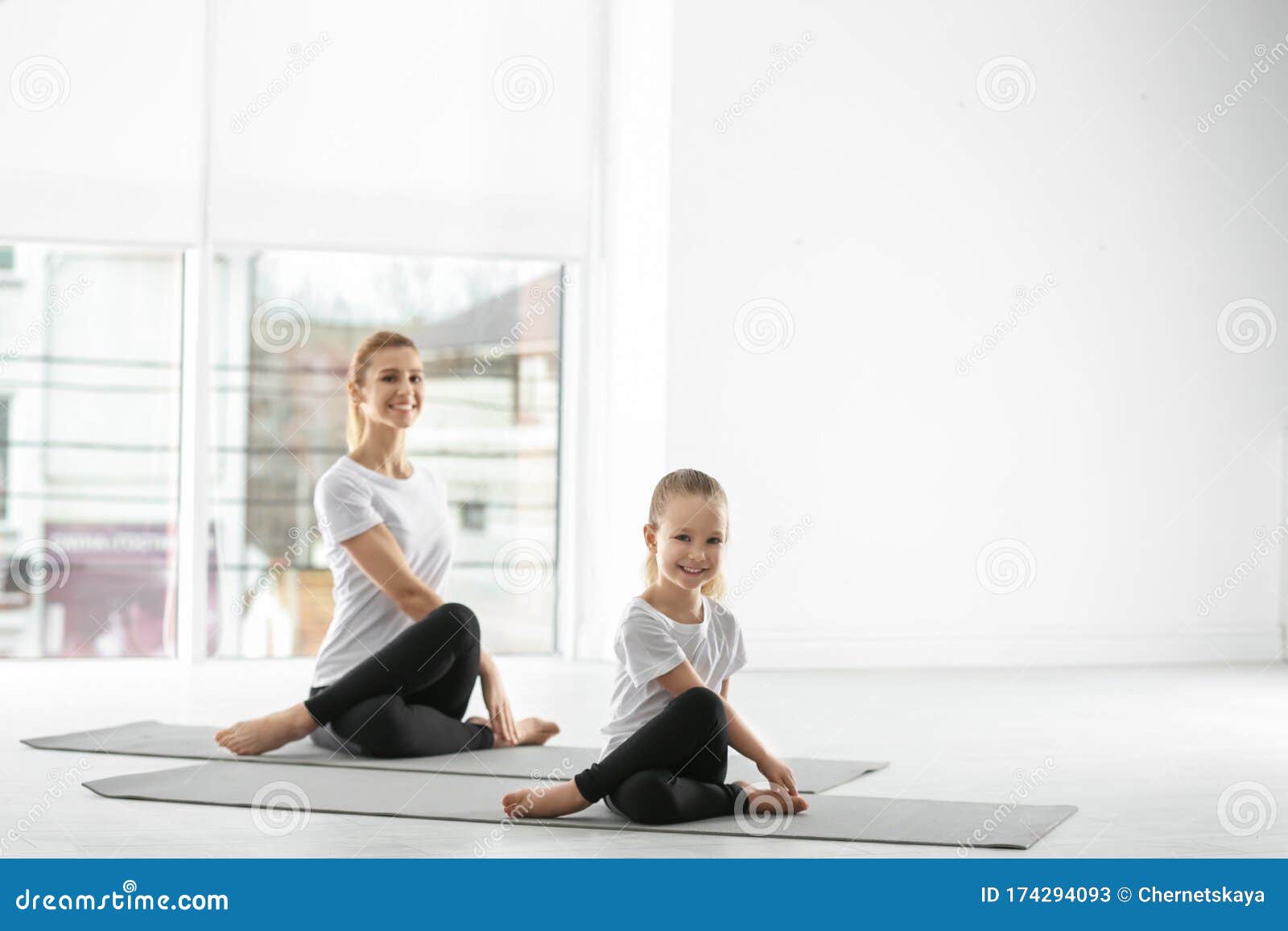 Mother And Daughter In Matching Sportswear Doing Yoga At