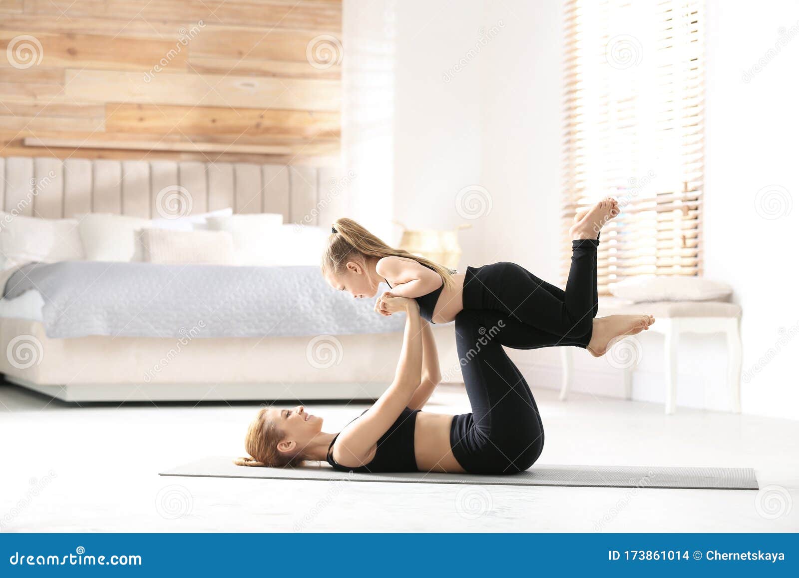 Mother And Daughter In Matching Sportswear Doing Yoga Near
