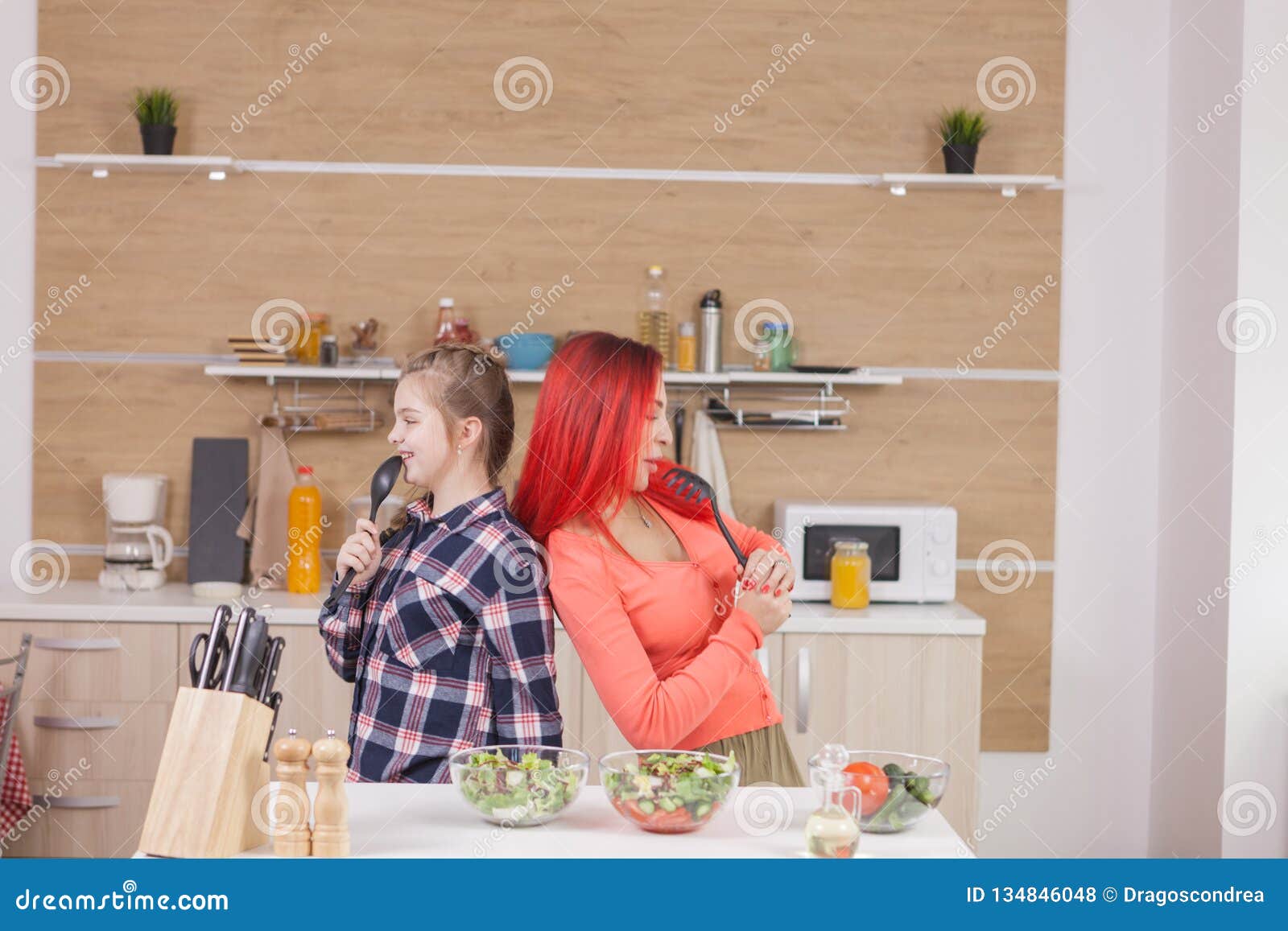 mother and daughter singing on kitchen intruments