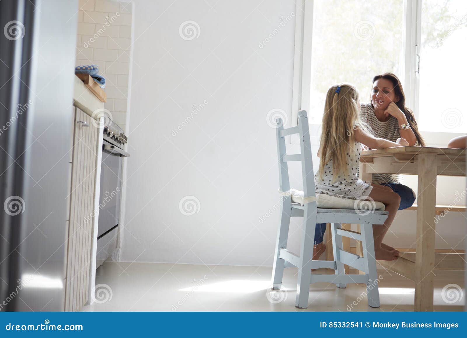 Mother and Daughter Sitting at Kitchen Table and Talking Stock Image