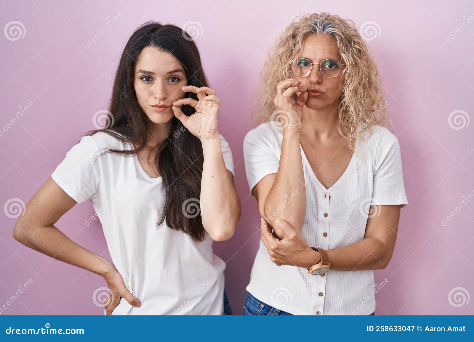 Mother and Daughter Standing Together Over Pink Background Mouth and