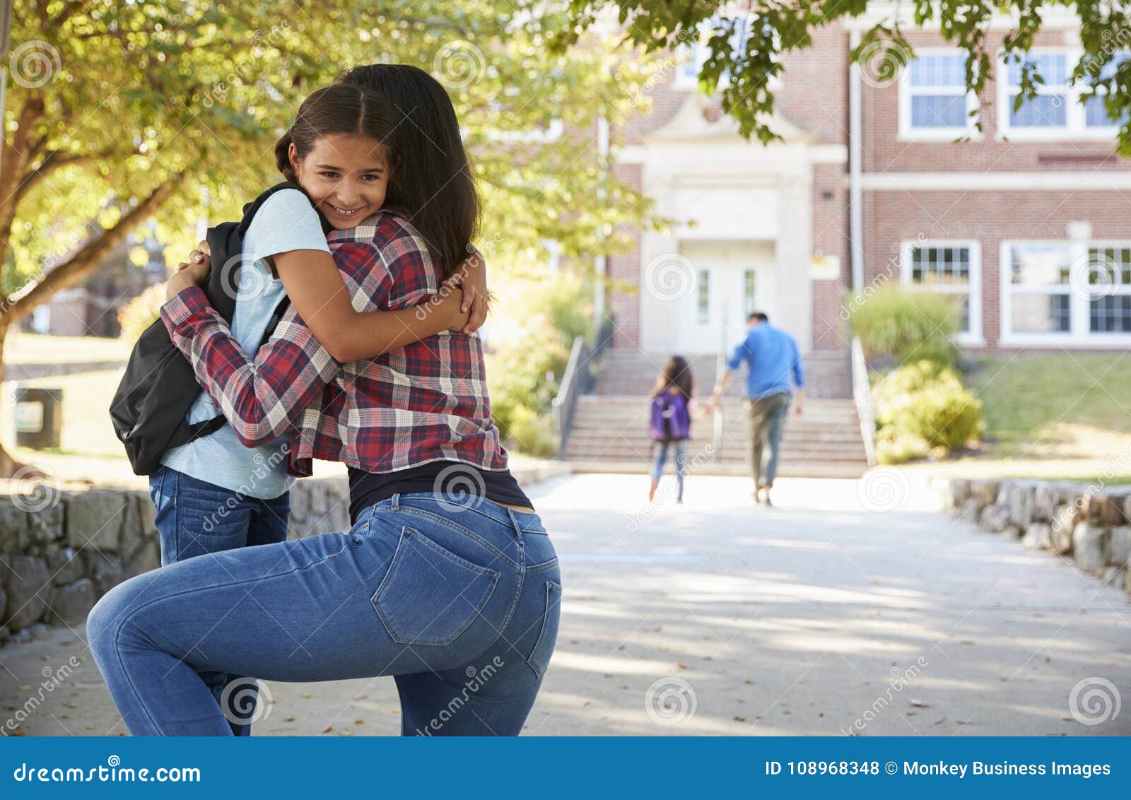 mother dropping off daughter in front of school gates