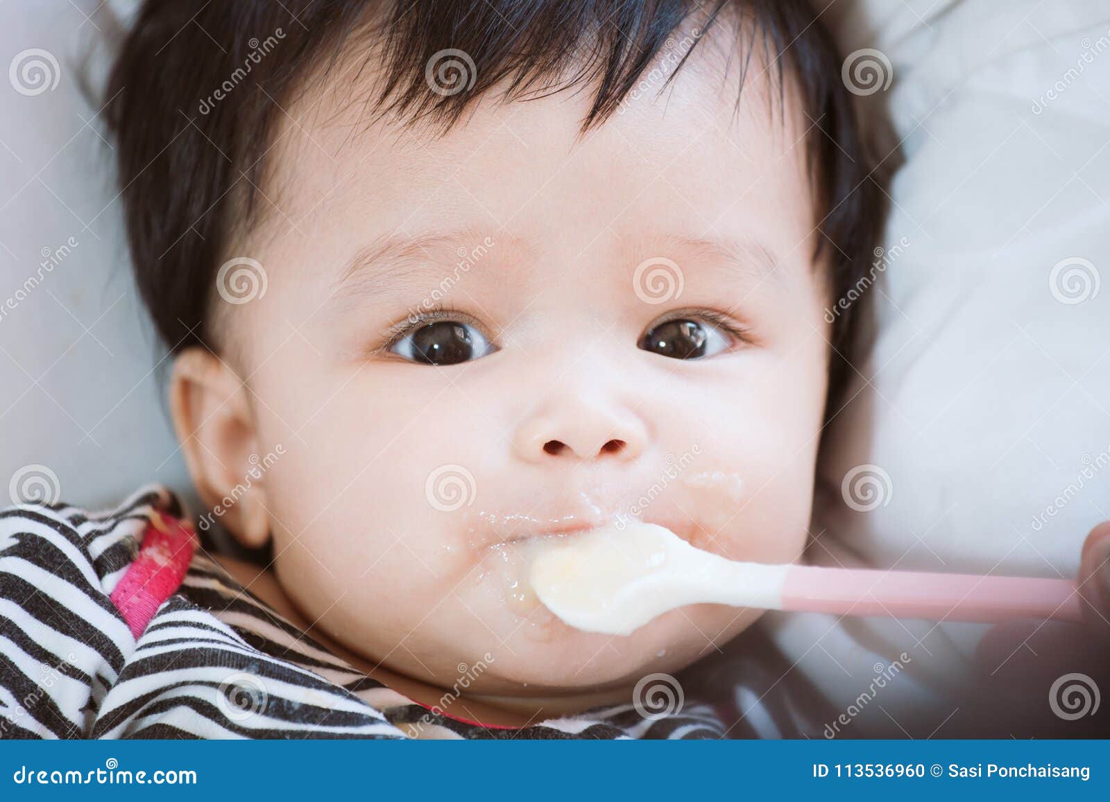 Mother Feeding Cute Asian Baby Girl With A Spoon At Home Stock Photo