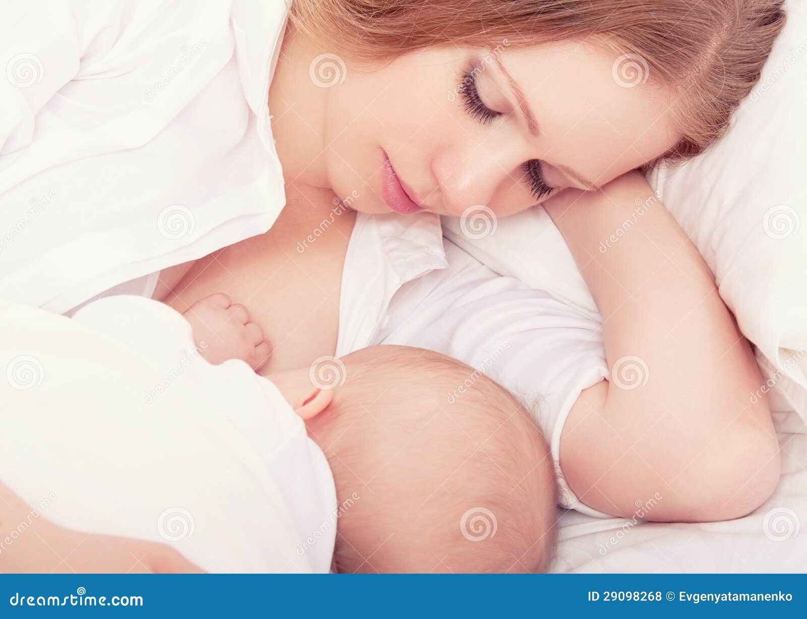 mother feeding her baby in the bed. sleeping together