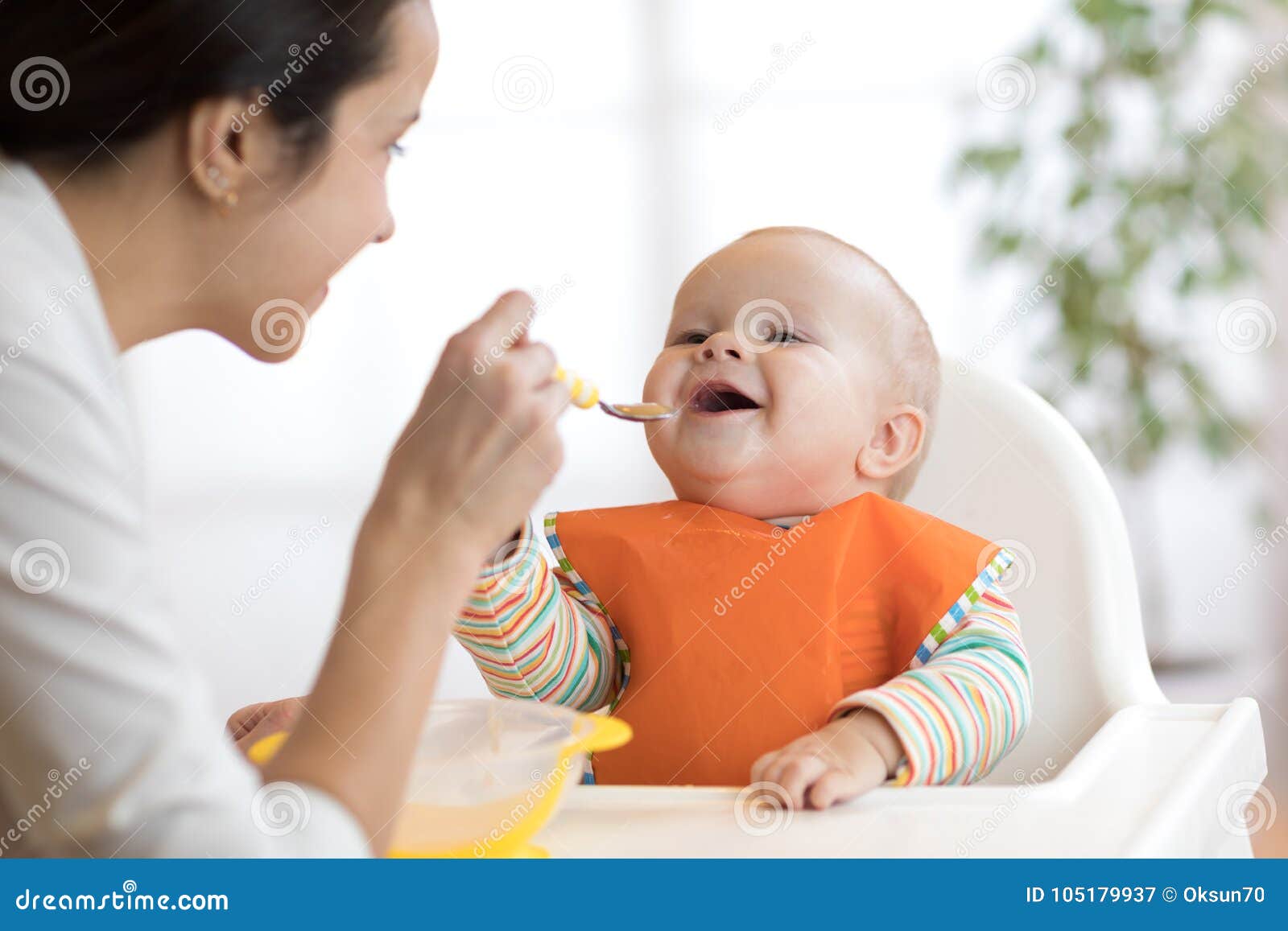 mother feeding her baby with spoon. mother giving healthy food to her adorable child at home