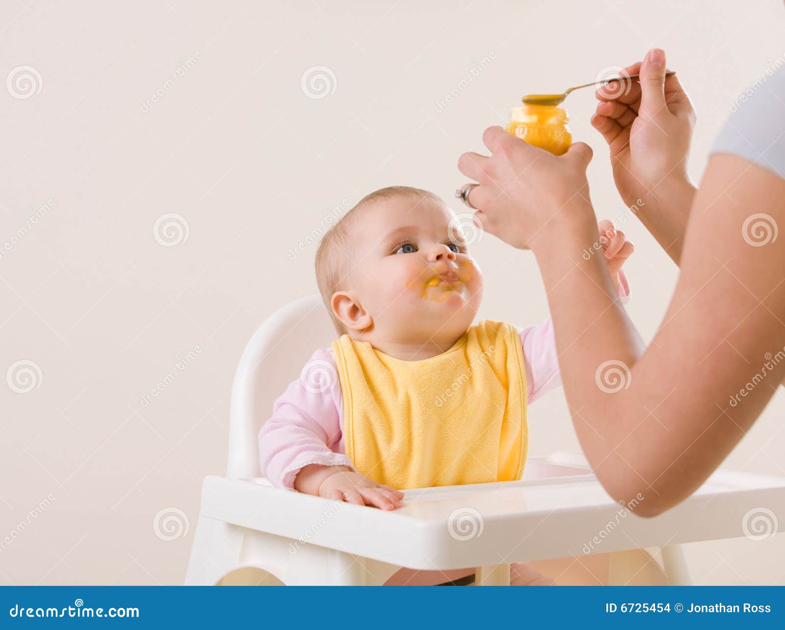 mother feeding hungry baby in highchair