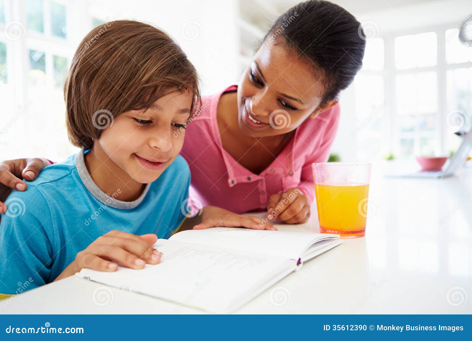 Mother Helping Son With Homework In Kitchen Stock Pho