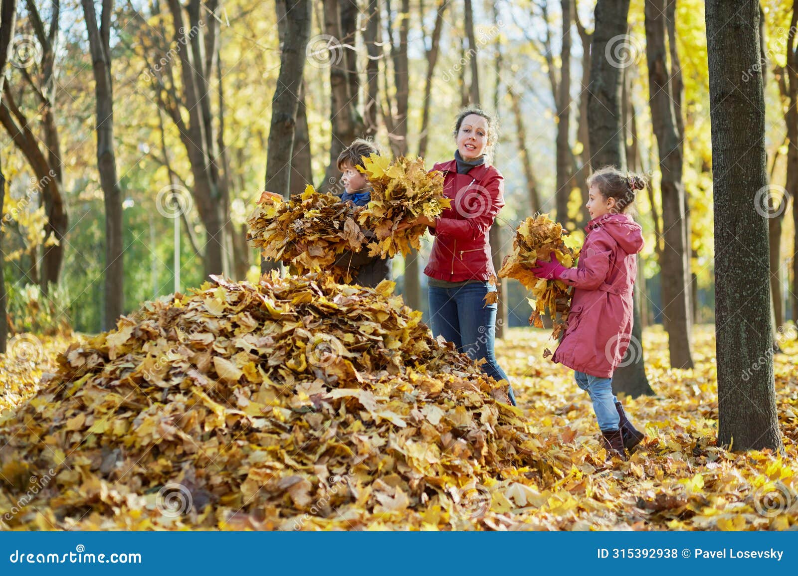 mother and her two children gather fallen leaves