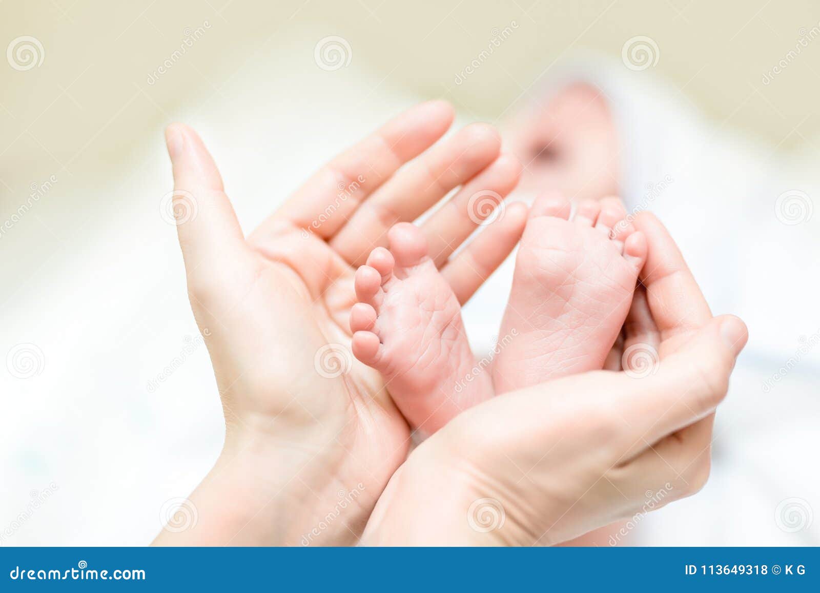 mother holding feet of newborn baby. infant legs in parent hand. child support and care. happy family