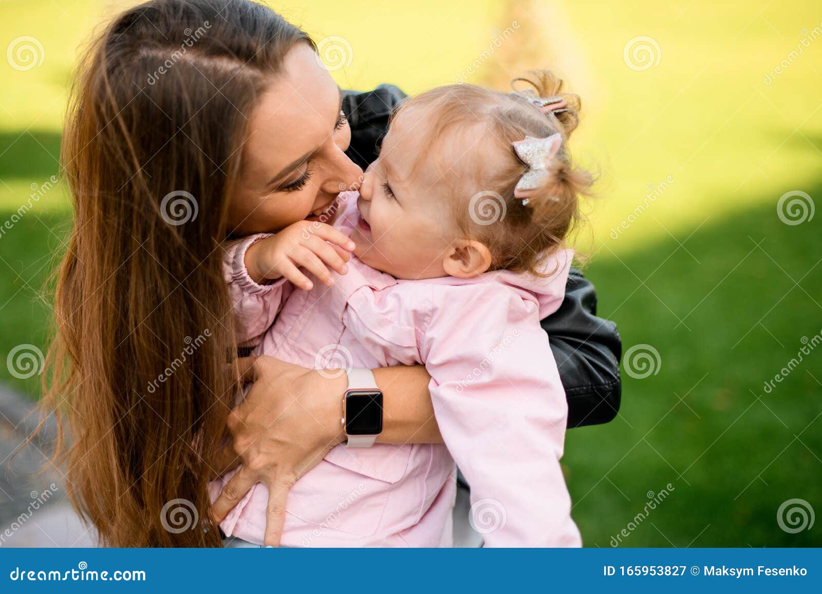 mother hugging her daughter holding in the armn touching noses