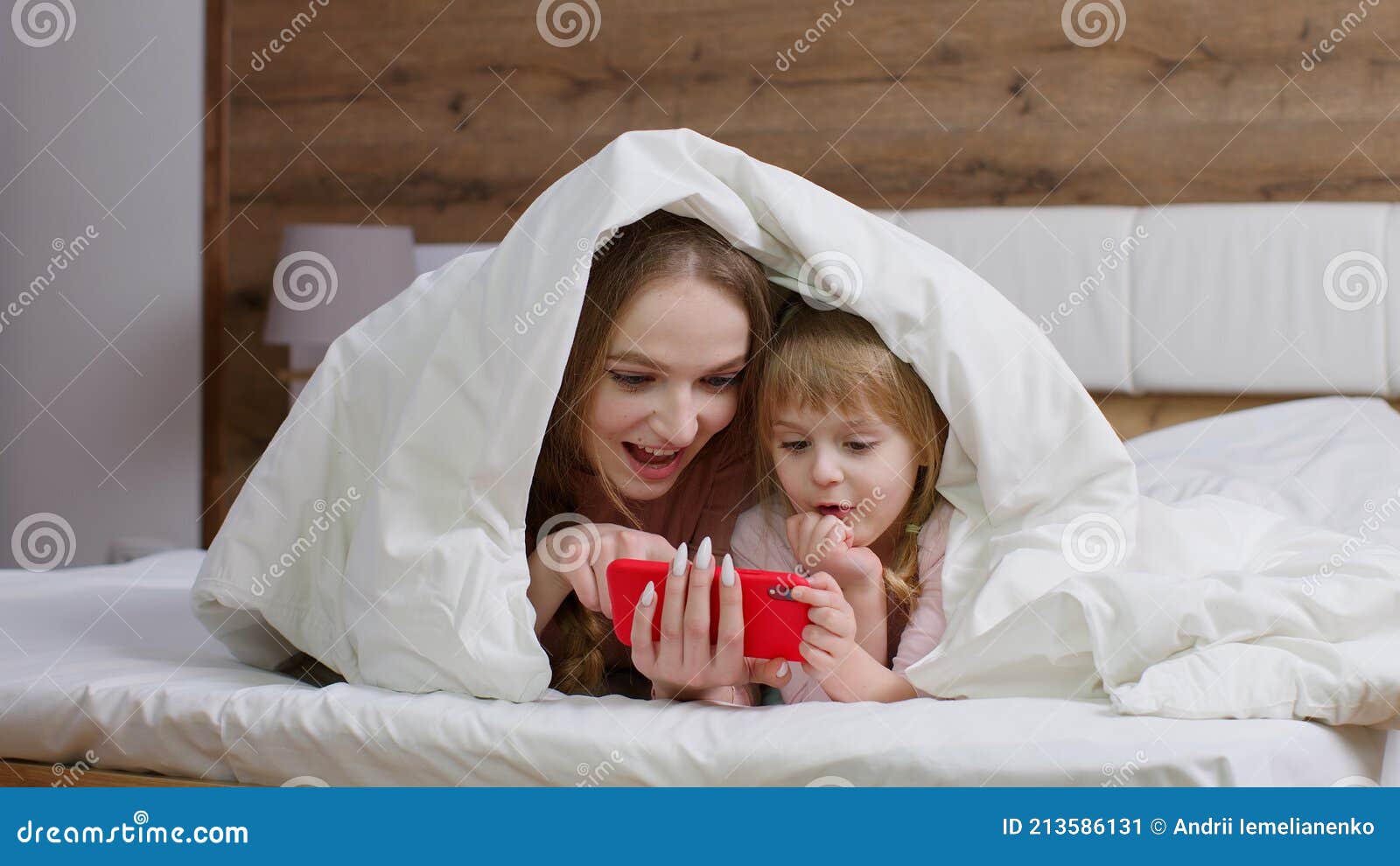 Mother Lying on Bed Under Duvet Blanket with Daughter Kid Girl Holding  Mobile Phone Watching Cartoon Stock Image - Image of internet, cartoons:  213586131
