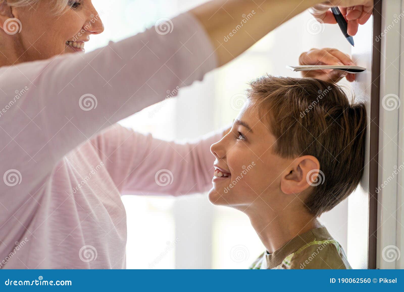 mother measuring the height of her son against wall
