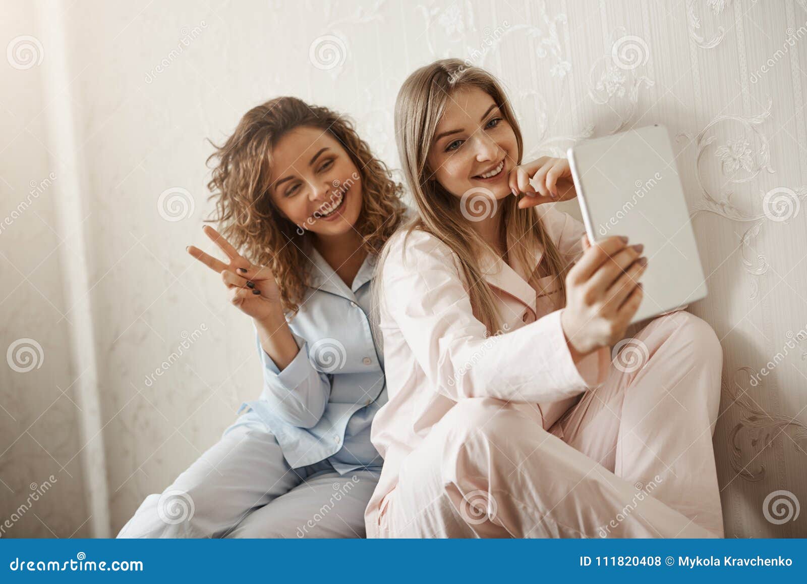 mother is my best friend forever. charming caucasian daughter in pyjamas taking selfie with mom using digital tablet