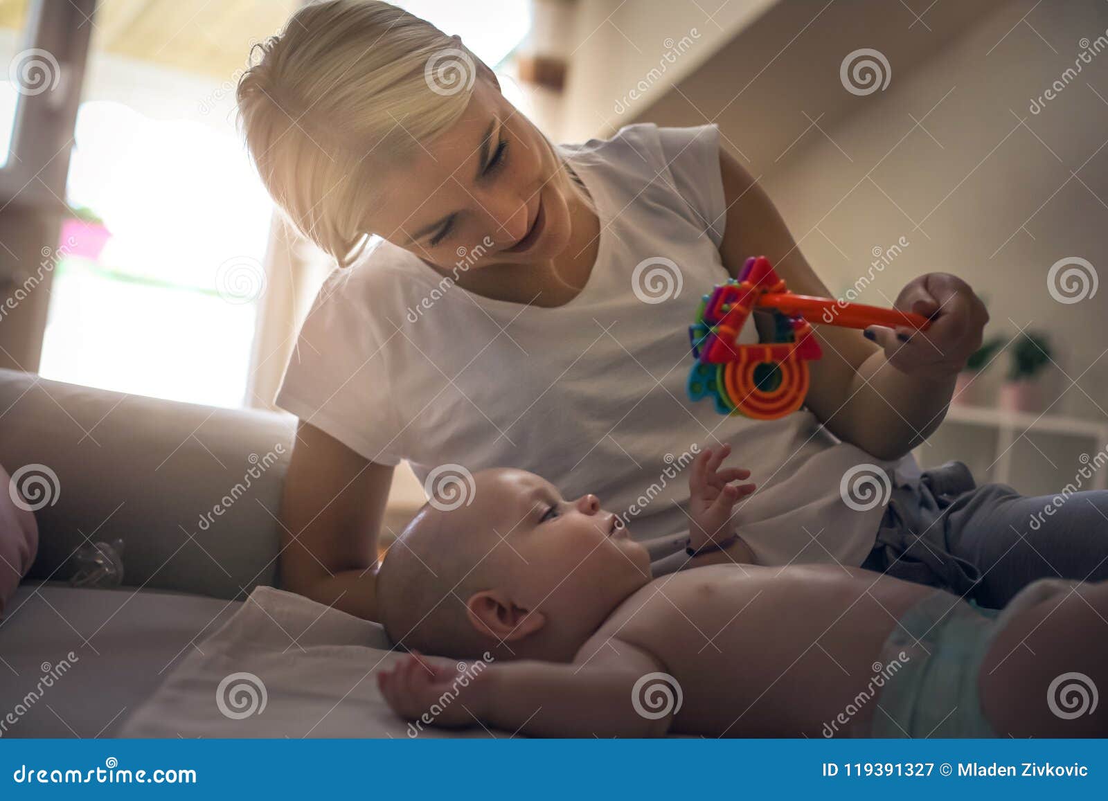 mother plying with her little baby boy at home and holdi