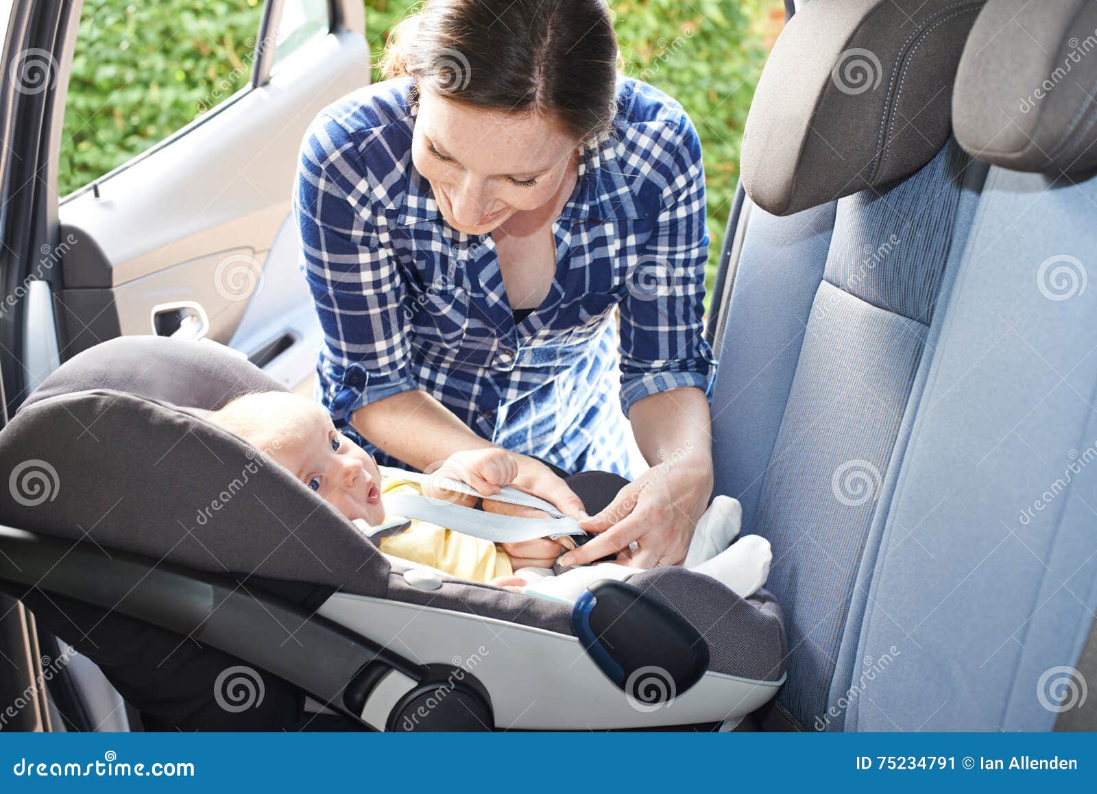 mother putting baby into car seat for journey