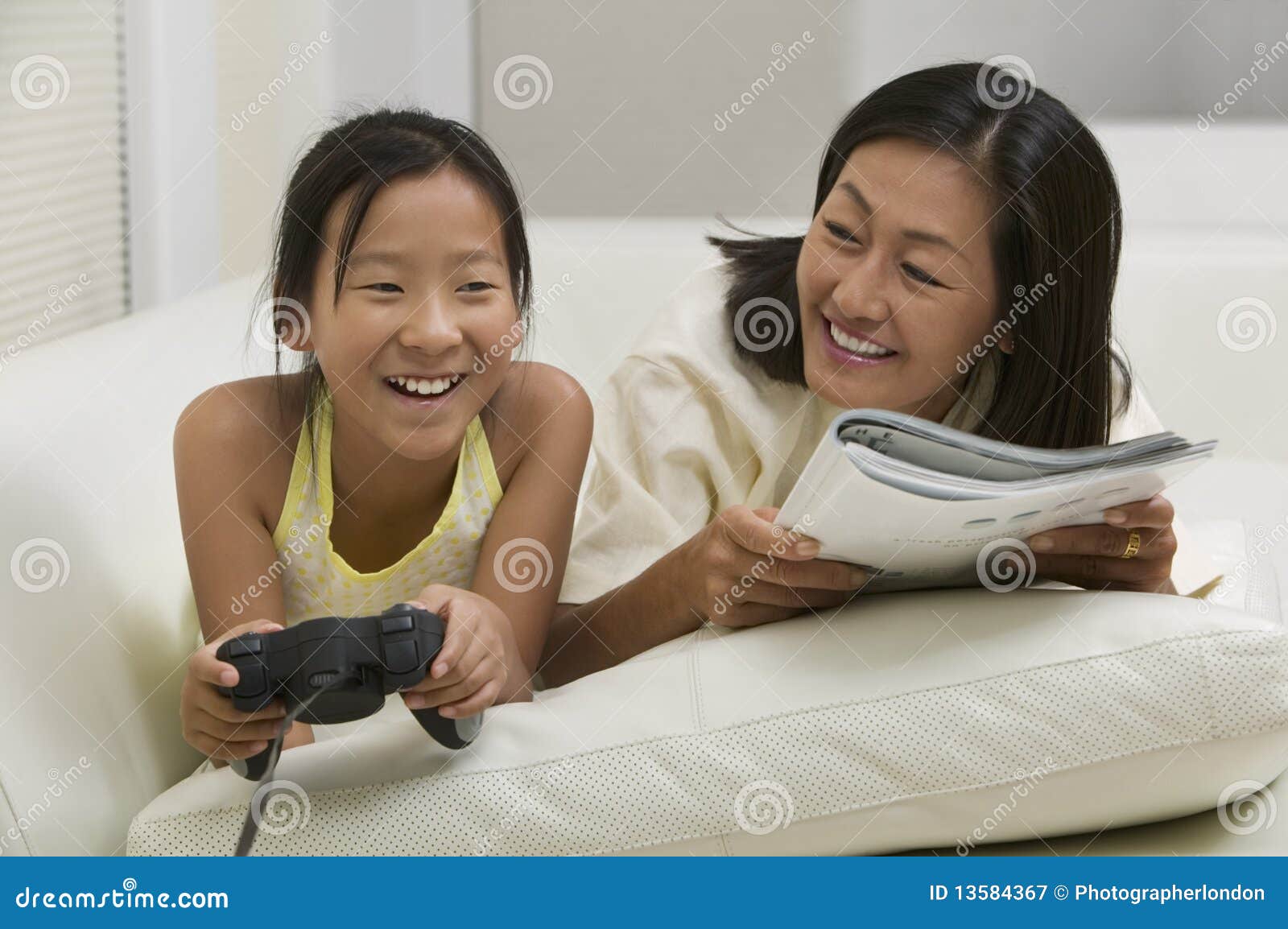 Mother Reading with Daughter Playing Video Game Stock Image Image of