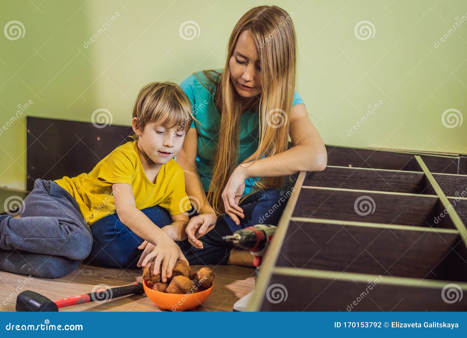 Mother And Son Assembling Furniture They Take A Break And Eat Cupcakes