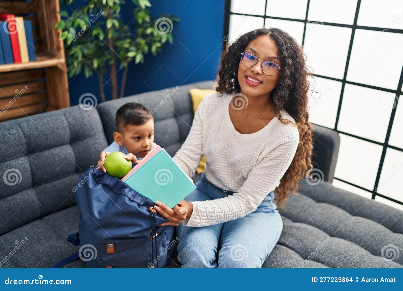 Mother and Son Prepare School Backpack Sitting on Sofa at Home Stock