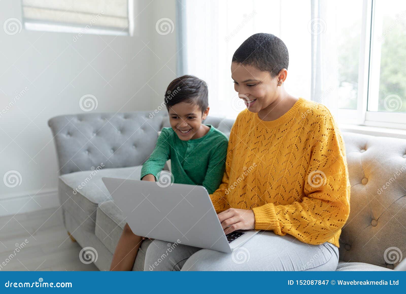Mother And Son Using Laptop On A Sofa In Living Room Stock Image